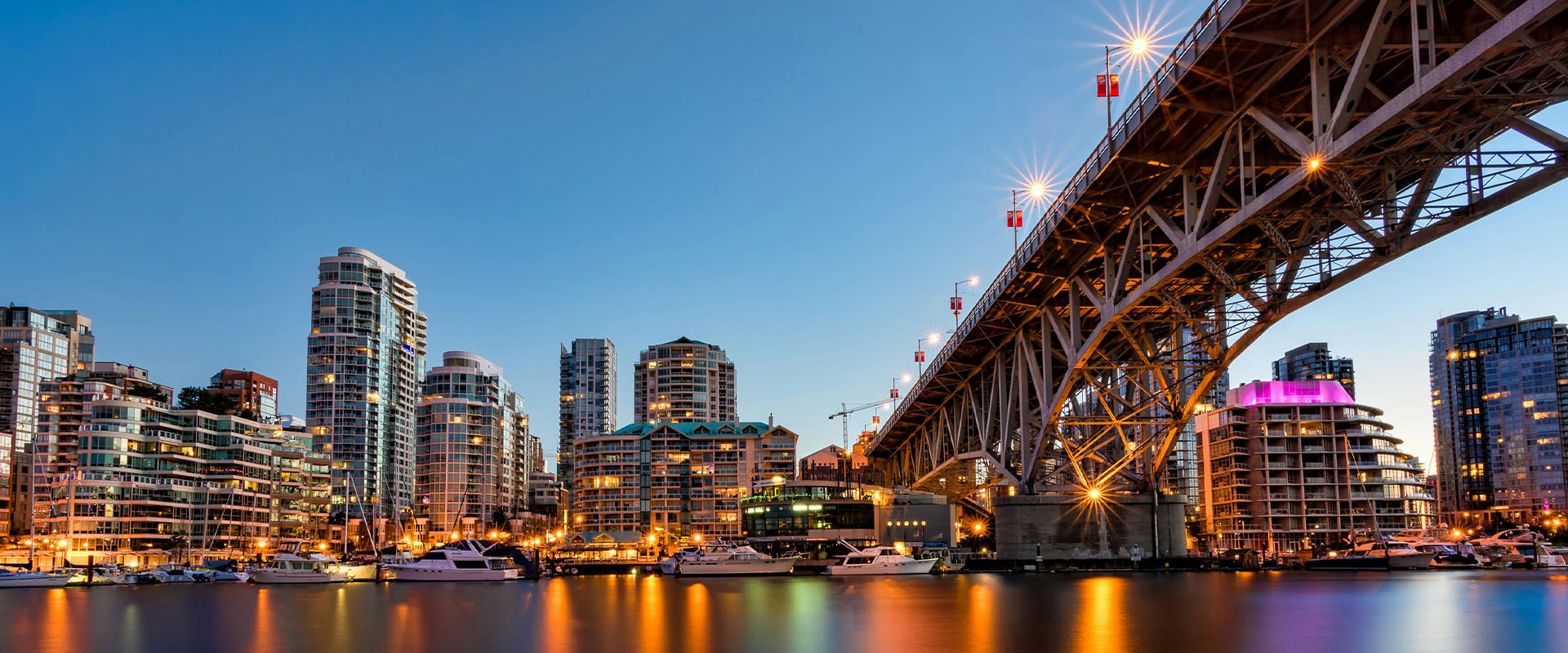 Granville island view from the water at dusk with bright city lights